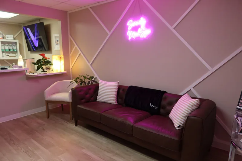 Reception lounge at Serenity Med Spa with the pink neon sign